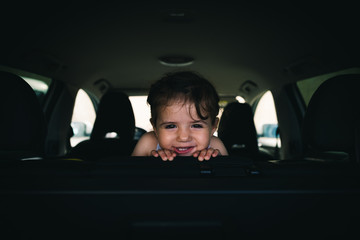 young girl with a cheeky, happy smile, sitting in the car