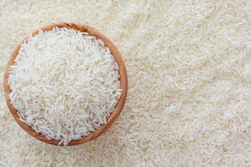 grains of Thai jasmine rice in wooden bowl on white rice background, top view with copy space, high resolution product.