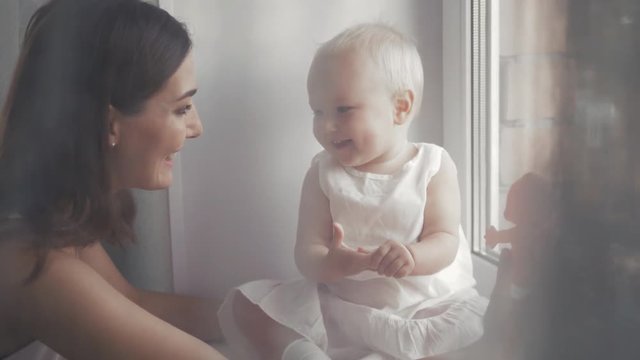 Young Happy Mother Holding her Newborn Child. Family at home. Beautiful smiling Mom and Happy Baby Together.
