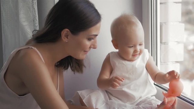 Young Happy Mother Holding her Newborn Child. Family at home. Beautiful smiling Mom and Happy Baby Together.