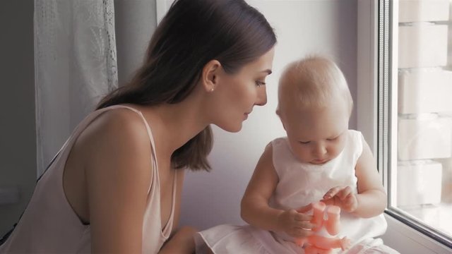 Young Happy Mother Holding her Newborn Child. Family at home. Beautiful smiling Mom and Happy Baby Together.