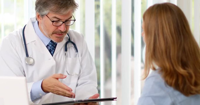 Doctor man talking sick patient woman in hospital.