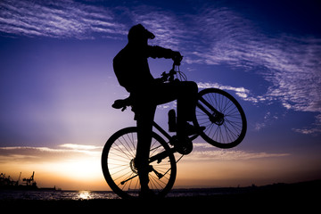 Silhouettes of biking man at beautiful sunset