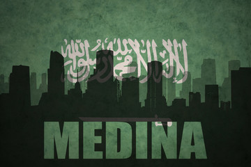 Fototapeta na wymiar abstract silhouette of the city with text Medina at the vintage saudi arabia flag background