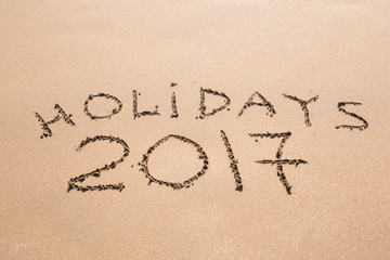 Happy Holidays 2017. Written in sand at the beach. Holiday, Christmas, New Year 2017 concept.