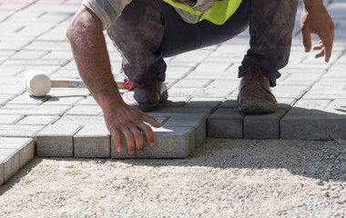 Worker puts sidewalk tile on the road