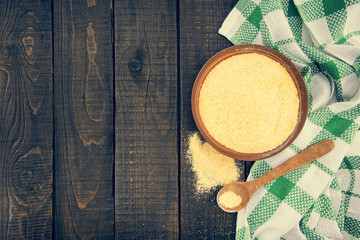 Yellow corn flour in a ceramic bowl on a rustic wooden table. In