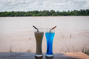 Glasses of tea and blue drink with Mekong river background