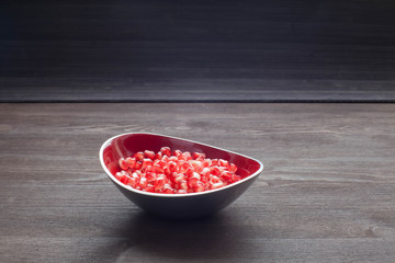 Berries pomegranate in plate on dark wooden background