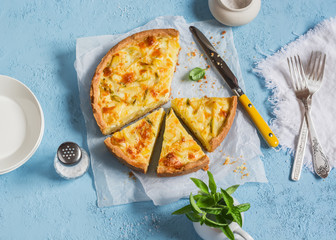 Leek, potato and cheese pie on a blue background, top view.