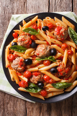 Italian Food: Pasta with meatballs, olives and tomato sauce closeup. Vertical top view