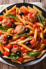 Penne pasta with meatballs and tomato sauce closeup. Vertical top view
