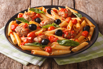 Italian cuisine: pasta penne with meatballs, olives and tomatoes close-up. horizontal
