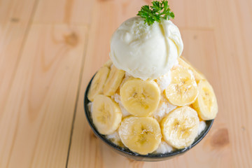 Korean style bing su fresh banana shaved ice on wood table .