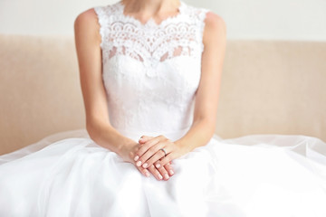 Bride in beautiful wedding gown sitting on sofa