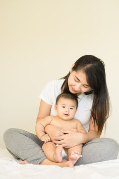 happy family.asian  mother playing with her baby in the bedroom.