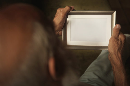 Old man holding and looking at photo frame
