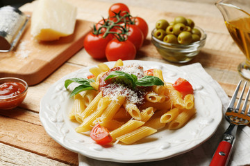Delicious penne pasta with ingredients on wooden table