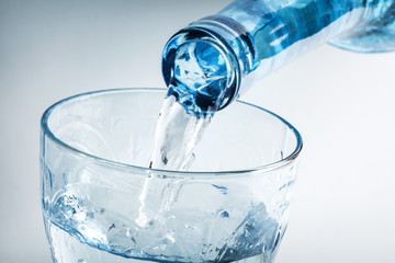 Pouring water on glass on white background