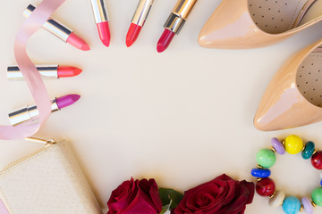 Nude colored high heels shoes with lipsticks, flowers and wallet hero header