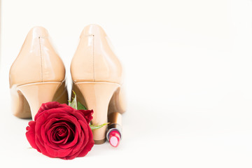 Nude colored high heels still life with red rose bud flower and lipstick
