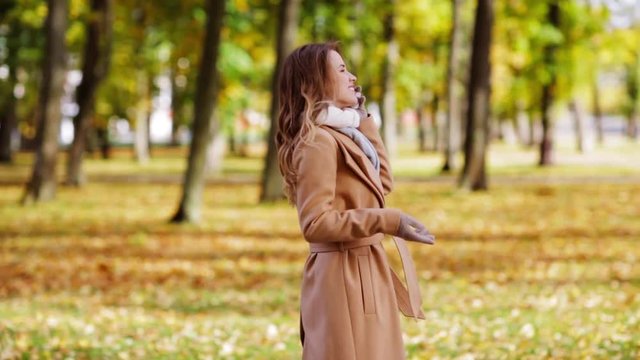 woman with smartphone walking in autumn park