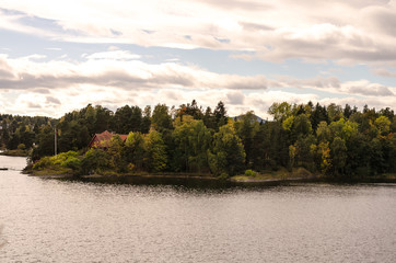 small red cottage house at a fjord and forest landscape