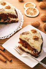 Piece of carrot cake with cheese cream on brown background.