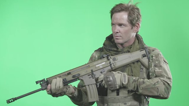 Soldier holding rifle, staring out in the distance on green screen