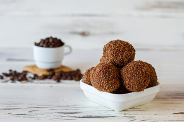 White bowl with sweets. Desserts of dark brown color. Tasty chocolate balls. Sugar and crumbled cookies.