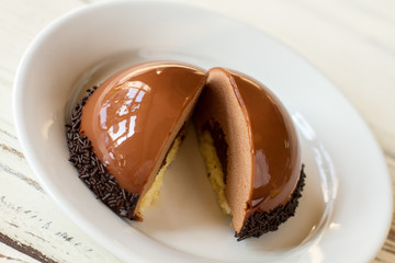 Sliced dessert on plate. Icing of brown color. Chocolate mousse cake in cafeteria. Freshly made sweet delicacy.