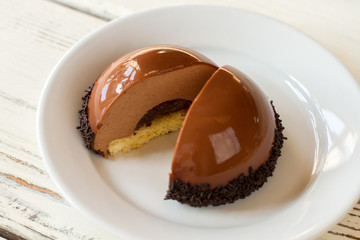 Sliced half sphere dessert. Thin layer of yellow dough. Chocolate mousse cake on plate. Tastiest delicacy in pastry cafe.