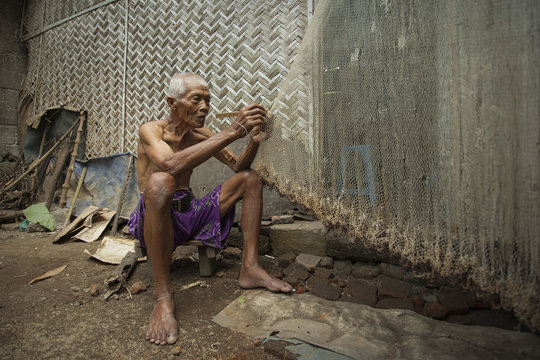 Senior man repairing a fishing net, Jember, East Java, Indonesia