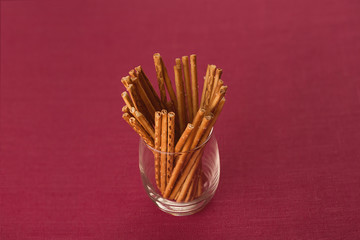 breadsticks, straws in the glass on 

the table. Burgundy linen background. Studio photography. Object