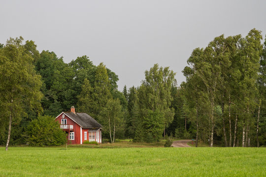 R&ouml;d stuga med vita knutar p&aring; sm&aring;l&auml;ndsk landsbygd