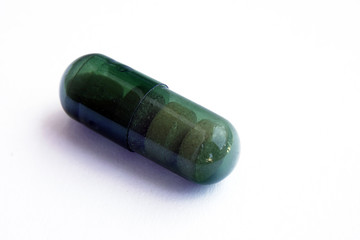 Green capsule pill on an isolated white background