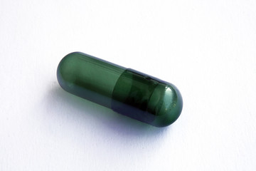 Green empty capsule pill on isolated white background