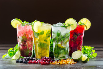 Different types of mojito cocktail on dark brown background