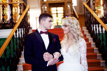 Beautiful young couple, the bride and groom go down the stairs. Luxurious interior