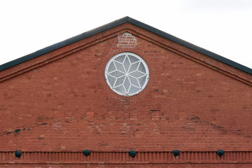 Crest of an old building with round window. Building made of bricks.