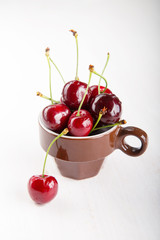 Obraz na płótnie Canvas Juicy fresh cherries in brown cup