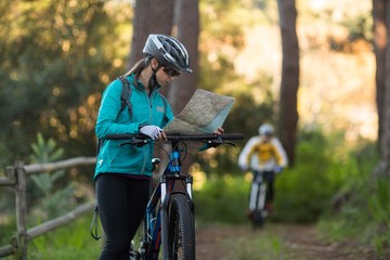 Female biker looking at a map with mountain bike
