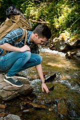 beautiful young guy tourist on the shore of a mountain river