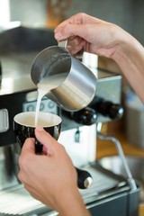 Waitress pouring milk in the cup