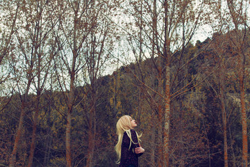 Mujer joven rubia sintiendo frío, sola en un bosque en otoño 
