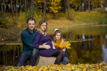 Happy pregnant family in autumn nature