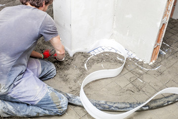 Employee performs sand and cement screed floor.