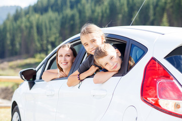 Happy young mom and her children sitting in a car