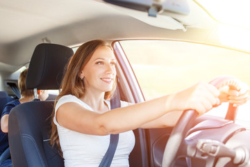 Smiling young woman driving a car at summer day