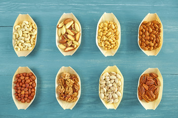 Nuts selection in wooden bowls on blue rustic table, view from above.